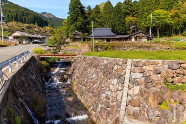 Su, dağ köyündeki geleneksel Japon evlerinin yanından akar. Yüksek kalite fotoğraf