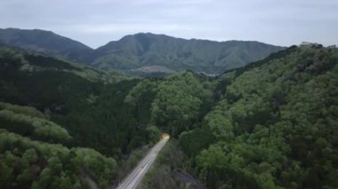 Alacakaranlıkta yeşil dağlarda otobanda tünelden çıkan arabaların hava görüntüsü. Yüksek kalite 4k görüntü