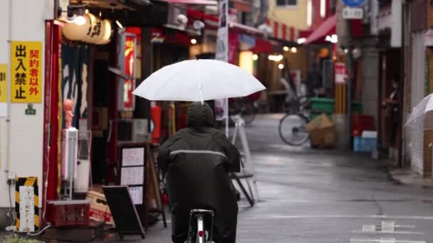 日本大阪 2023年4月29日 黄昏时分 骑着雨伞穿过日本小巷的骑自行车者 高质量的4K镜头 — 图库视频影像