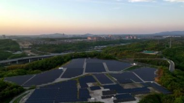 Gün batımında şehrin kenarında güneş panelleri ve otoban üzerinde uçmak. Yüksek kalite 4k görüntü