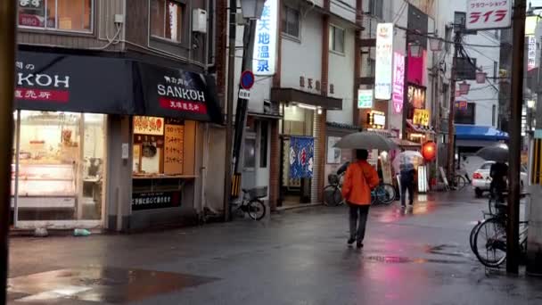 日本大阪 2023年4月29日 黄昏时分 骑雨伞的骑自行车穿过日本城市的雨街 高质量的4K镜头 — 图库视频影像