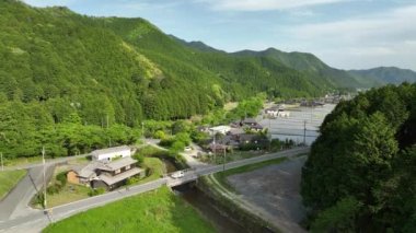 Kei kamyonu Japon evinin önünden geçiyor ve dağ manzarasında pirinç tarlalarını sular altında bırakıyor. Yüksek kalite 4k görüntü
