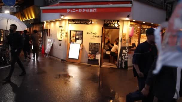 日本大阪 2023年4月29日 带着雨伞的人走在夜生活区点着灯的餐馆旁 高质量的4K镜头 — 图库视频影像