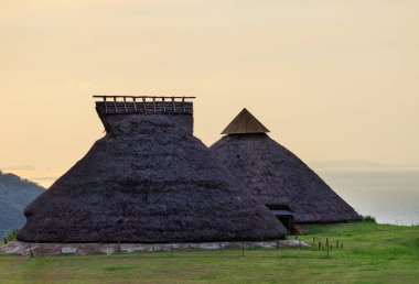 Jomon köyündeki çimenli sahil tepesinde tarihi sazdan çatı kulübeleri. Yüksek kalite fotoğraf