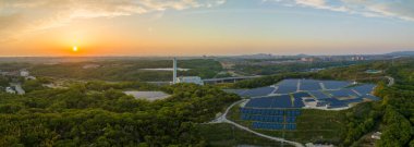 Panoramic aerial view of sunset on horizon and hilltop panels at solar farm. High quality photo clipart