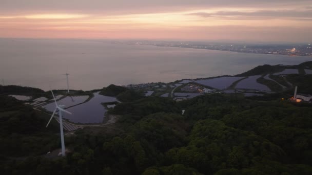 Kıyı Rüzgar Türbinleri Güneş Panelleri Gün Batımında Şehrin Uzak Işıklarına — Stok video