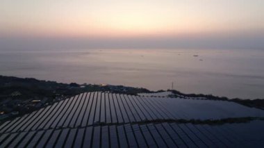 Güneş panelleri güneş batarken kıyıda sürdürülebilir enerji çiftliğinde. Yüksek kalite 4k görüntü