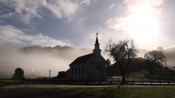 Frühmorgendlicher Nebel Und Strahlende Sonne Hinter Der Silhouette Einer Kirche — Stockvideo