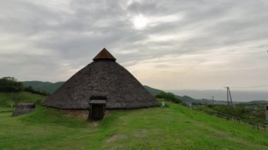 Jomon köyünün yeşil çimenlikteki tarihi sazdan çatılı kulübesine giriş. Yüksek kalite 4k görüntü
