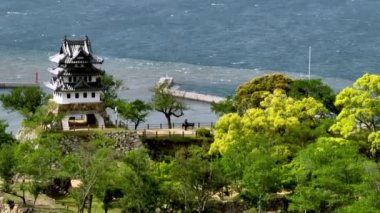 Japon şatosundaki tarihi ahşap kule kıyı kasabasına bakıyor. Yüksek kalite 4k görüntü