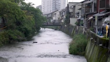 Yağmurlu günlerde geleneksel Japon evleri tarafından yönetilen nehirden aşağı akar. Yüksek kalite 4k görüntü