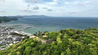 Küçük bir sahil kasabasına bakan tepedeki tarihi Japon şatosu. Yüksek kalite 4k görüntü