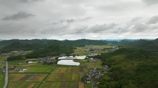 低い山脈の間の谷の畑や農家を飛び越える 高品質4K映像 — ストック動画