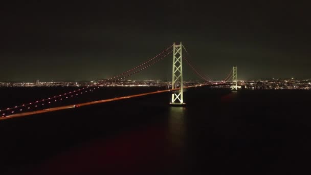 Über Autolampen Auf Der Hängebrücke Über Dunkles Wasser Die Stadt — Stockvideo