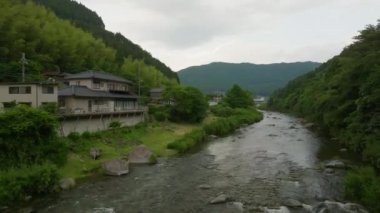 Japonya 'nın yeşil dağlarında akan nehir suyuyla evin üzerinden yükseliyor. Yüksek kalite 4k görüntü