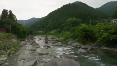 Kayaların üzerinden uçup nehirde akan sular yol ve yeşil dağlar. Yüksek kalite 4k görüntü
