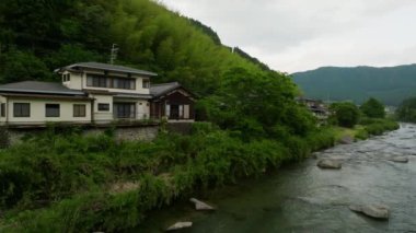 Nehir kenarındaki büyük Japon evi ve dağlardaki yemyeşil orman. Yüksek kalite 4k görüntü