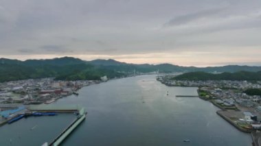 Gün batımında sahil kenti köprüsündeki araçları ortaya çıkarmak için geriye doğru uçuyorlar. Yüksek kalite 4k görüntü