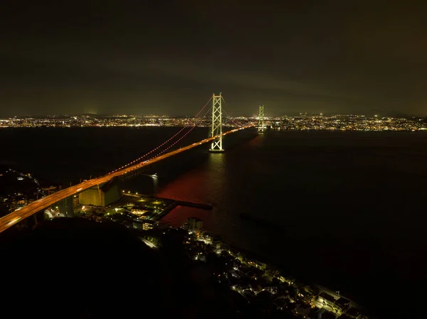 Подвесный Мост Акаси Кайкё Через Темную Воду Между Городскими Огнями — стоковое фото