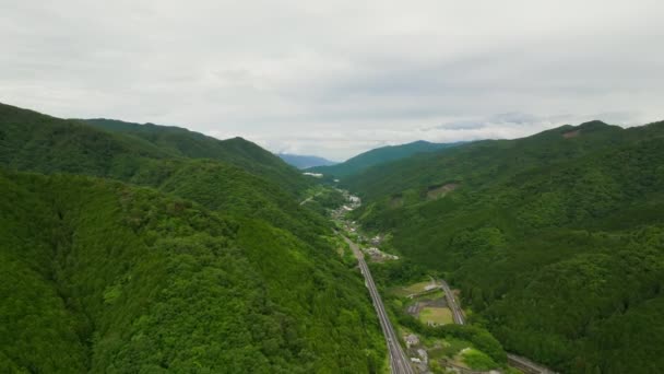 Voando Para Trás Sobre Estrada Reta Através Montanhas Verdes Florestadas — Vídeo de Stock