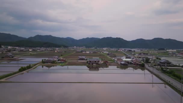 夕暮れの空は村の伝統的な家屋によって氾濫した水田に反映されます 高品質4K映像 — ストック動画