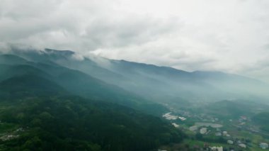 Yeşil kırsal kesimdeki evlerden dağlık alanda karamsar bir sis. Yüksek kalite 4k görüntü