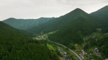 Köydeki küçük çiftlikler ve evler vasıtasıyla vadiden geçen yol manzaralı. Yüksek kalite 4k görüntü