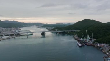 Gün batımında mavi suların üzerinden köprüye ve dağların kıyısına uçmak. Yüksek kalite 4k görüntü