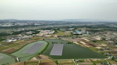 Flying over solar panels on reservoir by farms in rural landscape. High quality 4k footage