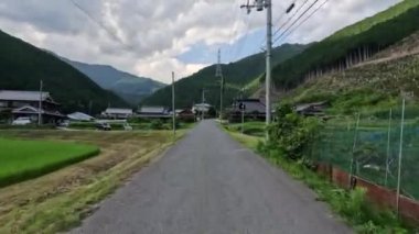 Japonya 'nın kırsal kesimindeki yeşil dağların yanındaki küçük bir köye giderken. Yüksek kalite 4k görüntü