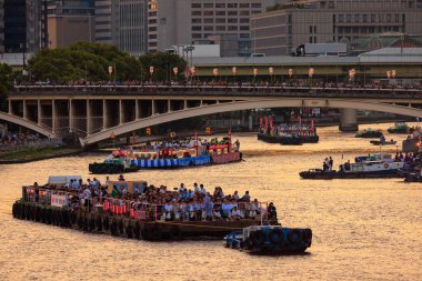 Osaka, Japonya - 25 Temmuz 2023 Tenjin Matsuri 'de kalabalık bir köprünün altında römorkörler tarafından çekilen mavna konvoyu. Yüksek kalite fotoğraf