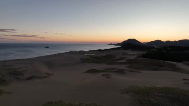 Terk edilmiş Tottori kum tepelerinin şafak vakti Japon Denizi kıyısındaki hava manzarası. Yüksek kalite 4k görüntü