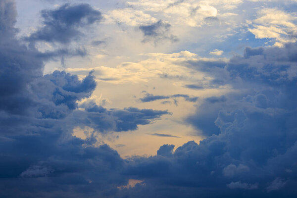 Golden light through towering blue clouds as storm approaches at sunset. High quality photo