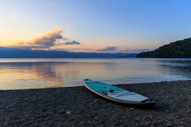 Gün batımında sessiz, boş plajda ayakta kürek çekme tahtası. Yüksek kalite fotoğraf