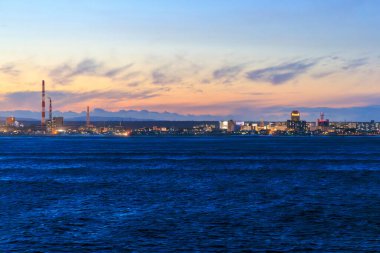 Hokkaido kıyısındaki Tomakomai şehrinde gün batımı gökyüzü ve baca yığını. Yüksek kalite fotoğraf