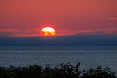 Parlak güneş ve alçak bulut okyanus ufkunda turuncu gün doğumu gökyüzünde parlıyor. Yüksek kalite fotoğraf