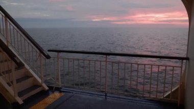Uzak ufukta gün batımı manzarası sakin ve açık okyanusta seyreden bir gemiden. Yüksek kalite 4k görüntü