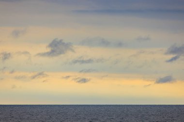 Gün doğumunda bulutlar ve sakin denizler arasındaki uzak ufuk. Yüksek kalite fotoğraf