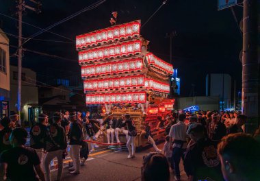 Kishiwada, Japonya - 17 Eylül 2023: Yorgun Danjiri katılımcıları geceleri taşınabilir tapınak fenerleri altında dinleniyor. Yüksek kalite fotoğraf