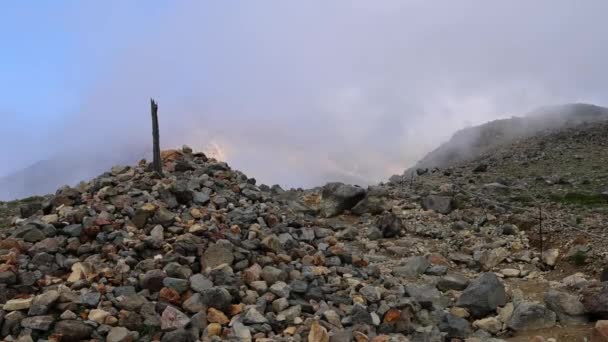 低い霧は山の斜面の岩の山の山のケルンそして木のポストの上に浮きます 高品質の4K映像 — ストック動画