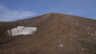Japonya 'nın Hokkaido kentindeki Asahidake zirvesine yakın kayalık, çorak arazide mevsim sonu kar tarlası. Yüksek kalite 4k görüntü