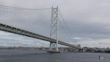 Ağır çekimde küçük teknelerle Akashi Köprüsü 'ne gidiyoruz. Yüksek kalite 4k görüntü