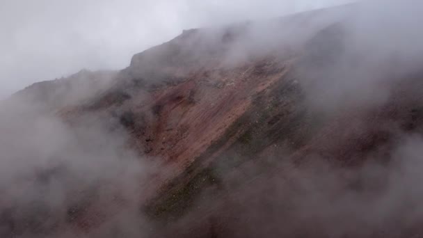 低霧と霧は火山山の頂上近くの急な岩の風景の上に浮かんでいる 高品質の4K映像 — ストック動画