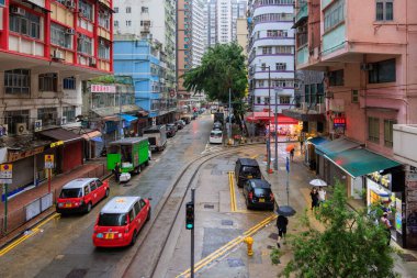 Hong Kong - 5 Eylül 2023: taksiler ve insanlar yağmur fırtınası sırasında ıslak sokaklarda yürürler. Yüksek kalite fotoğraf