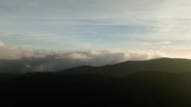 Gün doğumunda alçak bulutların siluetli dağ sırtı üzerindeki hava manzarası. Yüksek kalite 4k görüntü