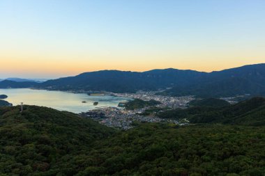 Sakin körfezdeki küçük bir sahil kasabasının dağ manzarası. Gün doğumu gökyüzünde parlıyor. Yüksek kalite fotoğraf