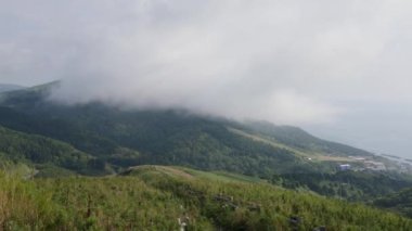 Güneşli bir günde Japonya 'nın Hokkaido kentindeki Rebun Adası sahilindeki yuvarlanan yeşil tepelerin alçak bulut ve sisi manzarası. Yüksek kalite 4k görüntü