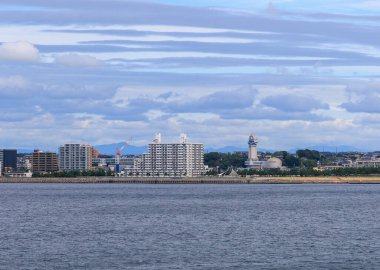 Akashi, Japonya - 23 Eylül 2023: Saat kulesi ve deniz kenarındaki apartmanlar bulutlu bir günde. Yüksek kalite fotoğraf