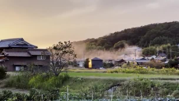 日本の田舎の伝統的な家々が日没時に火事から煙が上がる 高品質の4K映像 — ストック動画