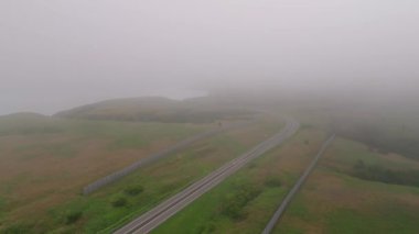 Yazın sonlarında engebeli Hokkaido sahilinde alçak siste açık yolda uçmak. Yüksek kalite 4k görüntü